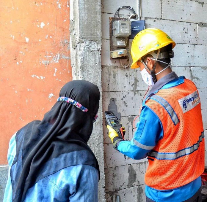 Petugas PLN tengah membantu warga dalam melakukan tambah daya.